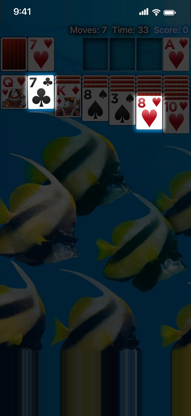 Real Solitaire on iPhone with a hint showing: the seven of clubs and the eight of hearts glow over a dimmed board.