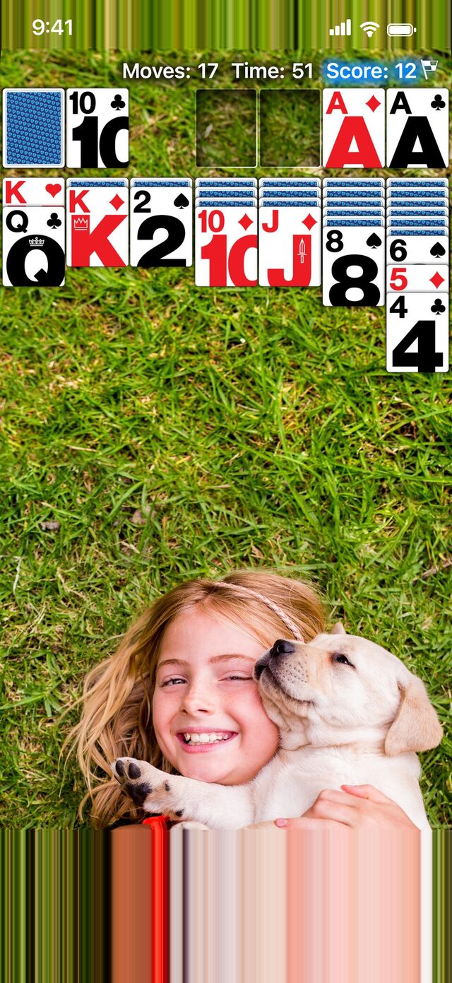 Real Solitaire on iPhone with a personal photo, a girl hugging a puppy, as the wallpaper.