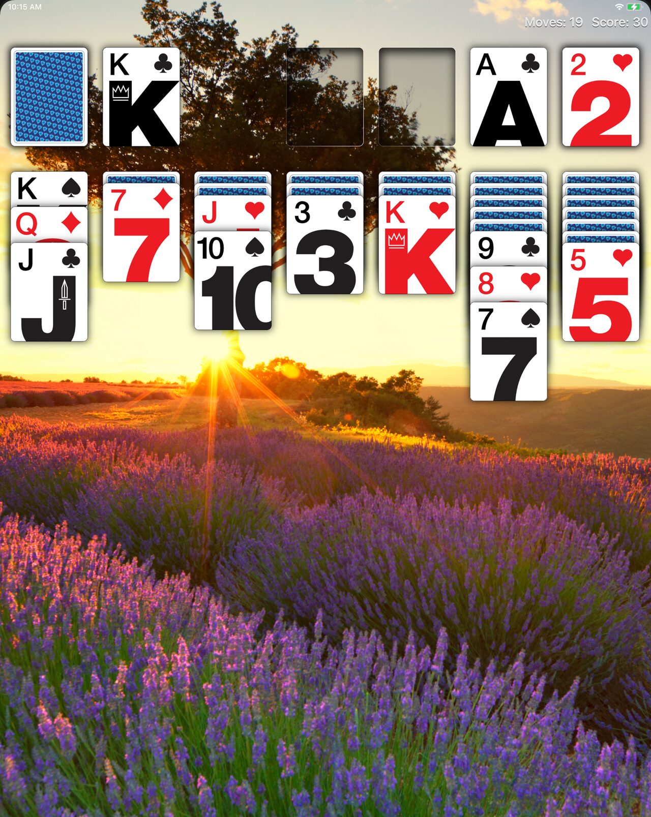 Real Solitaire on iPad with Modern cards over a photo of a lavender field at sunset.